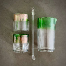 Load image into Gallery viewer, The Naturalist Cocktail Set - Alined in a grid, one mixing glass, one spoon, and two rocks glasses, all with a bright emerald green band of color.