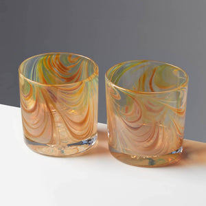 Pair of Oak Grain style cocktail glasses with amber and tan swirls against a contrasting gray background.