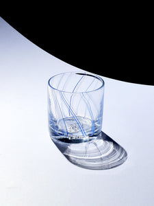 Rocks Glass with fine blue & white lines with a hard shadow capturing the pattern of the lines.