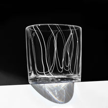 Load image into Gallery viewer, Simpatico in White rocks glass with vertical fine white lines against a dramatic black background.